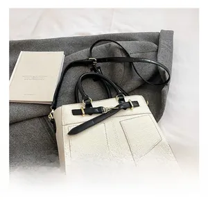 Close-up of lychee-textured cream leather bucket bag with gold hardware and black straps