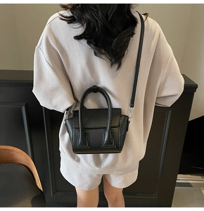 Rear view of a black lychee pattern leather handbag worn as a stylish crossbody bag