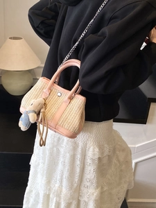 Pink leather trim straw woven handbag with chain strap and cute bear charm on model