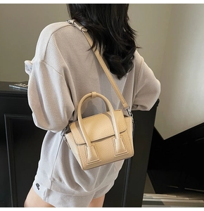 Detail of a creamy beige leather crossbody bag worn by a model to show size and texture