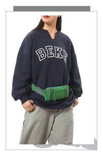 Close-up of waterproof nylon sports fanny pack in grass green on model wearing oversized hoodie