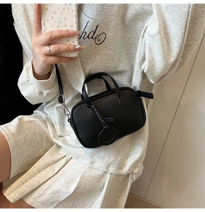 Mirror selfie showing the black lychee pattern leather mini crossbody bag with smiley charm