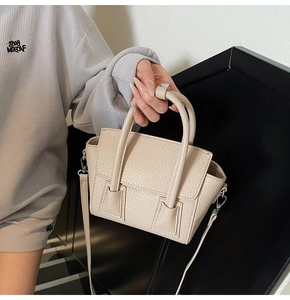 Detail of beige pebble leather handbag showing pebble texture and dual top handles