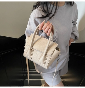 Detail of beige lychee grain faux leather handbag with silver hardware and dual handles