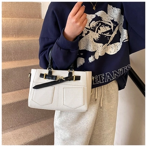 Detail of white litchi pattern leather handbag with contrast black handle and gold hardware