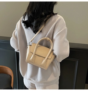 Detail of beige lychee texture leather handbag on model with detachable shoulder strap