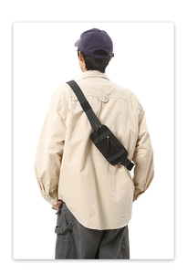 Rear view of a model wearing the adjustable black nylon crossbody sports bag