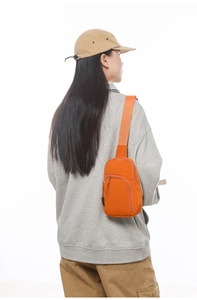Detail der leuchtend orangefarbenen Umhängetasche aus Nylon mit breitem Gurtband