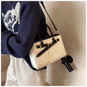 Detail of white lychee-patterned bucket bag with black strap and golden hardware