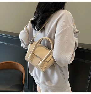 Minimalist beige pebble leather crossbody bag detail on model in grey attire