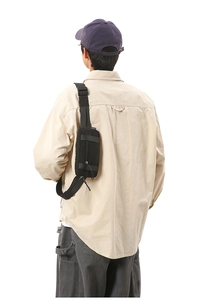 Rear view of a compact black nylon sports waist bag with adjustable strap on a male model