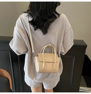 Model view of beige pebble leather mini crossbody bag with top handles and strap