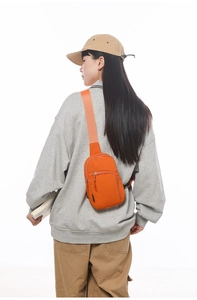 Seitenansicht einer leuchtend orangefarbenen Nylon-Umhängetasche an einem Model für den Alltag