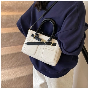 Lifestyle view of cream pebble leather bucket bag with black handles and side pocket details