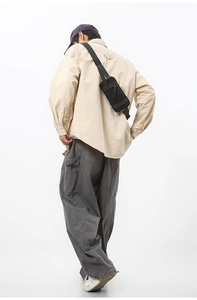 Rear view of a black nylon sports crossbody bag worn by a model in a minimalist style