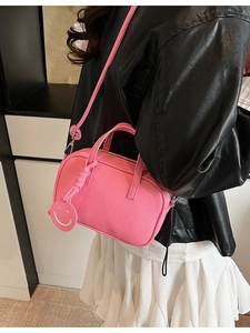 Pink lychee textured leather crossbody bag with adjustable strap and smiley face charm