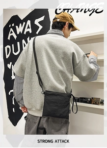 Detail view of black nylon crossbody bag worn with trendy streetwear layering style