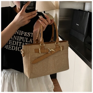Detail of a brown bucket bag with a denim-style pocket and gold-toned metal hardware