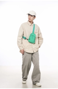 Frontansicht einer leuchtend grünen Crossbody-Brusttasche mit Reißverschlüssen am Model