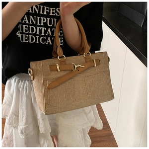 Detail of vintage brown tote bag showing textured fabric and polished gold hardware