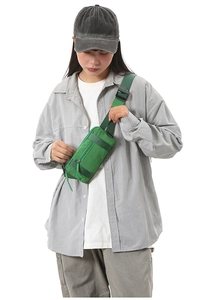 Close-up of green sports waist bag with multiple zippers shown on a model