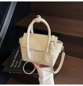 Detail of beige lychee grain leather handbag with silver buckle and shoulder strap