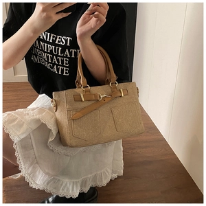 Detail of khaki bucket bag with textured fabric, brown leather straps and gold metal buckles