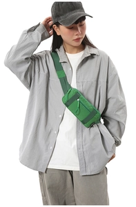 Detail of green nylon crossbody bag showing multiple zipper pockets and adjustable strap