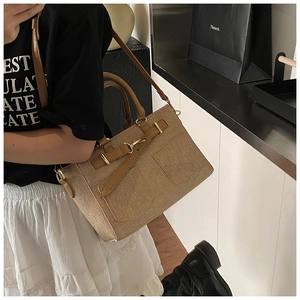 Detail of khaki woven crossbody bucket bag with brown leather trim worn by a model