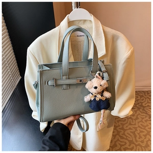 Detail of mint green lychee pattern leather handbag with a cute teddy bear charm