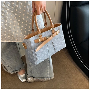 Close-up of stylish light blue bucket bag with brown leather straps and metal hardware