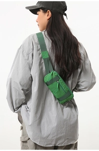 Detail view of emerald green nylon crossbody sports bag with wide strap and zipper design