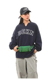 Close-up of a green nylon sports waist bag worn by a model in casual attire