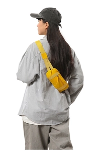 Back view of a yellow nylon sports fanny pack worn as a crossbody bag on white background