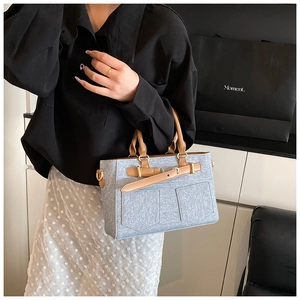 Detailed shot of stylish light blue canvas bucket bag with brown leather accents