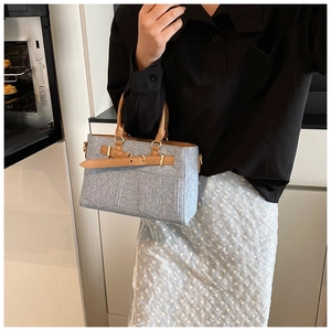 Detail of grey-blue denim texture handbag with brown faux leather straps and pockets