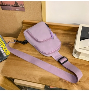 Draufsicht einer lila Nylon-Umhängetasche auf Holztisch mit Outdoor-Lifestyle-Magazinen