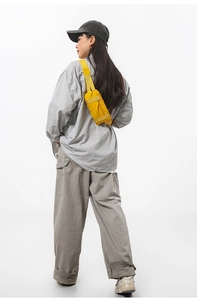 Rear view of model wearing a yellow nylon crossbody bag with adjustable wide strap