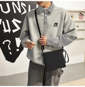 Close-up of a black square nylon crossbody bag worn with a grey casual streetwear outfit