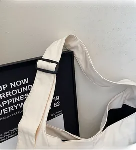 Détail de la bandoulière large réglable avec boucle noire sur un sac beige chic