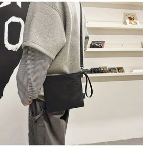 Close-up of black canvas sacoche bag with adjustable strap worn by a person