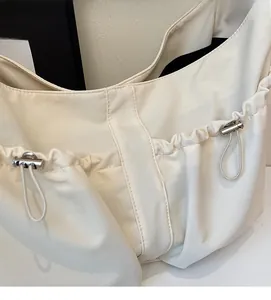 Détail du sac à bandoulière en nylon blanc avec cordon décoratif et boucle en métal