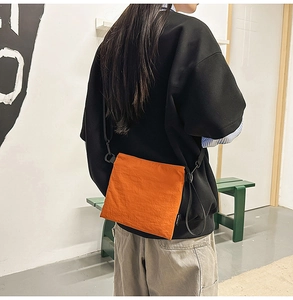 Close-up of bright orange nylon envelope bag with adjustable black shoulder strap