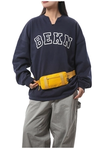 Close-up of yellow lightweight waterproof nylon waist bag worn with navy blue sweatshirt