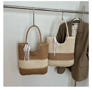 Detail of hand-woven straw tote bags with contrast stripes and decorative lace ribbons