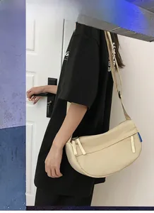 Detail of beige half-moon nylon crossbody bag showing the blue brand tag and texture