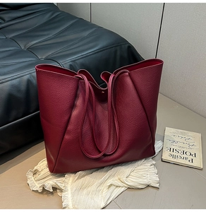 Makroaufnahme der burgunderroten Lychee-Ledertextur und Magnetverschluss der Tasche