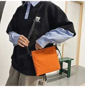 Detail of bright orange nylon crossbody bag with adjustable strap on a male model