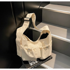 Détail du sac cabas en nylon blanc cassé avec bandoulière réglable et poche latérale à cordon