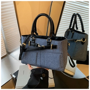 Detailed shot of navy denim handbag with black leather straps and gold metal hardware
